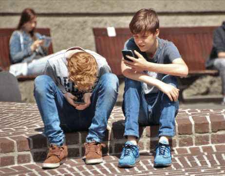 Two teenaged boys looking at their phones
