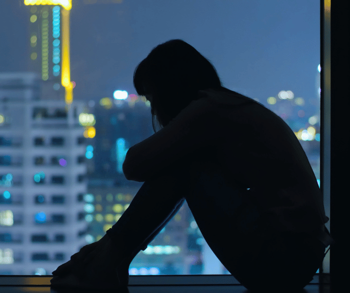 Silhouette of woman sitting on a windowsill